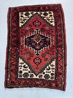 Complete view of the rectangular Persian Saveh rug showing full pattern and borders in red, navy blue, and beige with floral and geometric motifs.