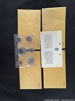 Photo showing two brown envelopes, one open with six coins in sealed plastic packaging, and a government descriptive card.