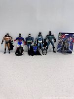 Seven assorted action figures mainly Batman and Superman related, standing in a row, including one new in box figure.