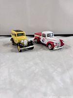 Front view of two diecast models: yellow 1932 Ford Delivery Van and white/red 1940 Ford Pepsi Cola Delivery Truck.