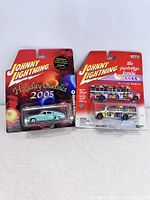 Front view of two Johnny Lightning die-cast cars in original packaging, one Holiday Classics 2005 Coke car and one Partridge Family bus.