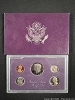 1985 US Mint Proof Set in purple presentation case with embossed US Great Seal on cover, showing 5 proof coins inside clear holder.