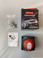 Full lot showing the Ampper branded battery switch, mounting screws in a small plastic bag, instruction manual, and original product box with car image.