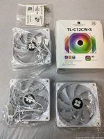 Three Thermalright TL-C12CW-S RGB computer cooling fans, white frames with transparent blades, cables attached, original box and mounting screws visible