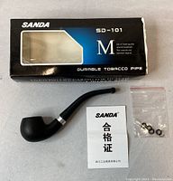 Photo of the SANDA tobacco pipe SD-101 with original box, instruction leaflet, and small accessories in a plastic bag.