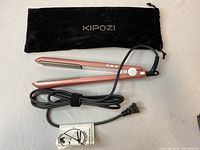 Kipozi hair straightener in rose gold with power cord and black soft pouch laid flat