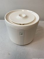 Front view of the white plastic pet water dispenser showing the top lid and overall compact design.