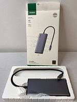Boxed Ugreen Revodok 8-in-1 USB-C Hub with device taken out of packaging, showing front side with attached USB-C cable