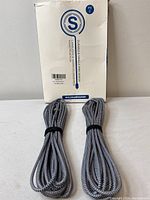 Two coiled grey and white nylon braided charging cables with a package behind them indicating they are durable and tangle-resistant design.