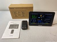 Full lot overview including the weather station in operation, wireless sensor, user manual, and original packaging box.