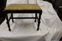 Front view of vintage wooden bench showing turned legs and upholstered seat