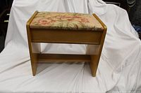 Front view of small wooden bench with floral fabric cushioned seat and open lower shelf.