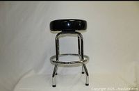 Side view of black padded bar stool with chrome legs and ring footrest, showing stool height and design.