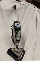 Full view of Hoover Floormate SteamScrub Touch steam cleaner showing upright handle, triangular base with mounted cleaning pads, and touch control panel.