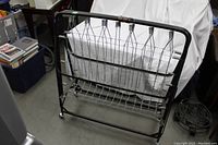 Front view of folded metal folding bed frame showing black metal construction and spring-supported mesh.