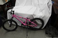 Side view of pink Kona Makena children's bike showing full frame, tires, handlebars, and missing seat.
