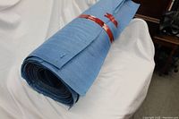 Rolled-up blue floor underlay padding with a red band securing it, placed on a white background.