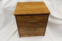 Front view of wooden nightstand showing natural woodgrain finish and two closed drawers with brass handles.