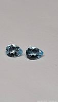 Pair of pear shaped, faceted sky blue topaz stones on white background