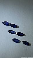Six marquis cut blue sapphires arranged on a surface, showing color and clarity.