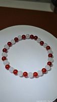 Top-down view of bracelet laid in a circular shape on white surface showing alternating pattern of red Carnelian and white Jade beads.