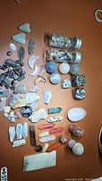 Overview of the large assortment of mixed crystals and stones including small vials, spheres, rough and polished stones on a brown surface