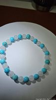 Top-down view of natural white jade and robin's egg turquoise bead bracelet on white surface, showing bead color and size.
