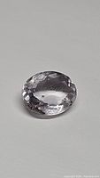 Oval cut natural pink amethyst gemstone shown clearly with faceted surface and slight internal inclusions visible.