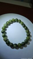 Top view of the natural green jade bracelet showing consistent bead size and slight variegation in green hues.