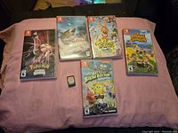 All five game cases arranged on surface with one loose cartridge at center