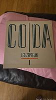 Front cover of Led Zeppelin CODA album showing beige cover with large CODA text and band name.