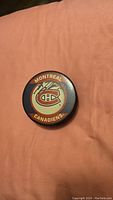 Top view of the hockey puck showing the Montreal Canadiens logo and signatures.