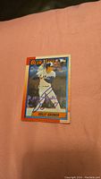 Photo of Kelly Gruber 1989 Topps baseball card signed in blue ink, showing front of card against a pink background.