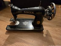 Side view of vintage Singer sewing machine showing gold decorative detailing and 'Singer' branding.