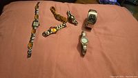 Six different wristwatches laid out on fabric, shows variety of styles and bands.