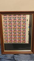 Frontal photo showing the full sheet of Elvis Presley 29 cent stamps in a wood framed display.
