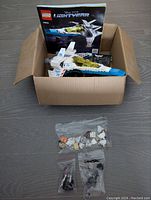 Photo of Lego Lightyear starship with instruction manual in box along with small bags of Lego pieces.