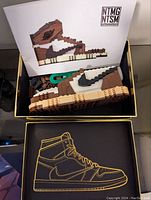 Box with assembled plastic building block sneaker resembling Air Jordan Cactus Jack and instruction manual inside.