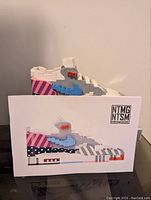 Side profile of constructed LEGO shoe model representing Nike Air Max 1 Parra sneaker displayed on white branded backdrop.