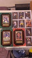 Photo showing the full lot with framed cards and multiple football cards in toploaders arranged in two sheets.
