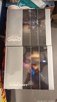 Two sealed large hardcover collector's art books from Blizzard featuring Warcraft and StarCraft cinematic art, showing the front covers