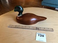 Side view of the mallard decoy showing smooth wooden body and ruler for size reference.