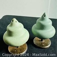 Front view of two green sculptural salt and pepper shakers on silver bases