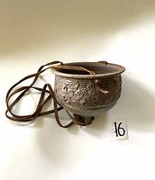 Full view of the mid-century pottery hanging planter showing the round shape, textured relief design, and attached suede hanging cord.