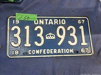 Photo of a blue metal license plate with white text '313 931', 'ONTARIO', and 'CONFEDERATION' from 1967.