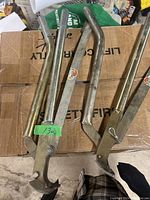 Two metal bead breakers on cardboard surface, showing condition and hooks for tire bead breaking.