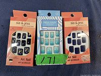 Three unopened packs of fake nails, two from Sia & Jess Salon Collection and one from Deja Vous Collection, displayed on dark fabric background.