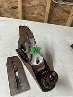 Footprint wood hand plane with metal body, wooden handle, and a separate wooden plane blade cover on a workbench.