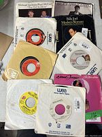 Vinyl records including singles and albums by Michael Jackson, Paul McCartney, Bruce Springsteen, Billy Joel, Donna Summer, and others shown in a stacked arrangement.