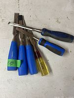 Five chisels laid out on a surface, showing variety in handle colors and sizes.